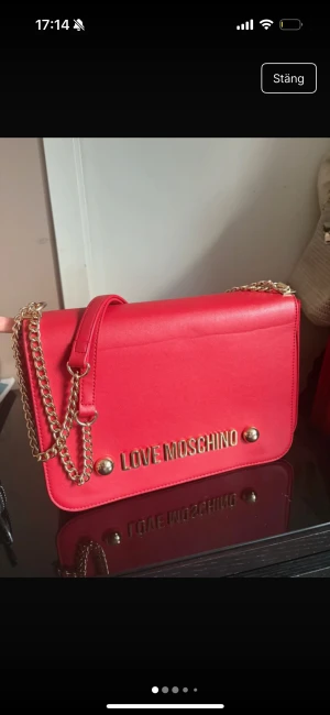 Röd axelväska från Love Moschino - Snygg röd axelväska från Love Moschino med guldfärgade kedjor och detaljer.  använt fåtal gånger, men är som ny. Så snygg