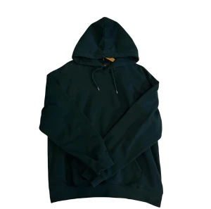 Mörkgrön hoodie från H&M loose fit - Snygg mörkgrön hoodie från H&M i loose fit-modell. Tröjan har huva med snörning, långa ärmar och en klassisk känguruficka framtill. Perfekt för chill dagar och enkel att matcha med jeans eller joggers.