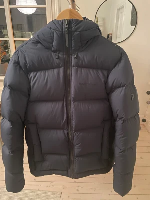 Mörkblå Peak Performance dunjacka - Säljer en mörkblå vinterjacka från Peak Performance i storlek M. Nyskick, endast använd fåtal gånger nypris drygt 4000