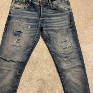 Jack n jones jeans - Säljer nu ett par tvär feta Jack & Jones jeans, som är i toppen skick och som är i färgen blå, jeansen har lite slitningar från knä och upp, men som är jätte bra gjorda och inget som går igenom, ställ gärna frågor!!!