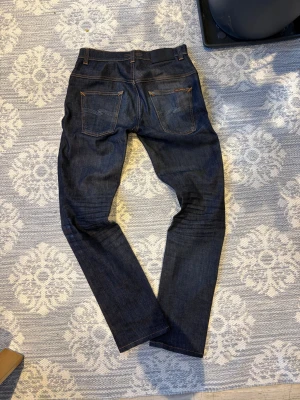 Nudie jeans thin finn dry dips - Säljer ett par mörkblå jeans från Nudie Jeans i modellen Thinn finn. Klassisk femficksdesign och orangea kontrastsömmar. Mycket fins skick och inte tecken på användning hör av er om ni har några frågor MVH theo