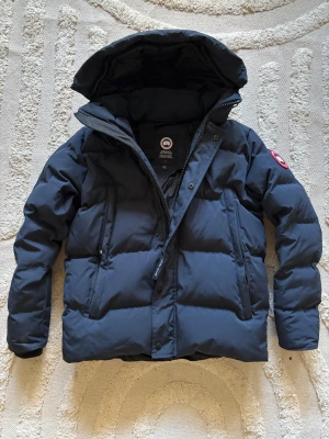 Canada Goose Wyndham jacka - Säljer en mörkblå Canada Goose Wyndham jacka i strl M, mycket bra skick och inga skador! Pros går att diskuteras 