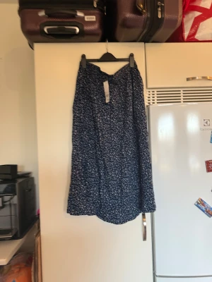 Blommig blå långkjol från Mywear Woman - Säljer en flowy långkjol från Mywear Woman i storlek L. Kjolen är mörkblå med små blommor i ljusblått och vitt, har resår i midjan och är gjord i ett lätt och mjukt material som känns skönt mot huden. Perfekt för dig som gillar blommigt och vill ha en chill look. Helt ny med tags/ prislapp fortfarande kvar. 