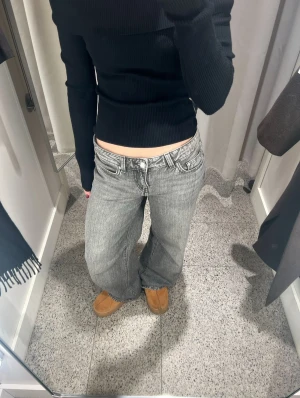 Lågmidjade grå jeans från Gina Tricot  - Lågmidjade, gråa jeans från Gina Tricot. Något baggy i passformen och vida i benen. Använda men i gott skick.