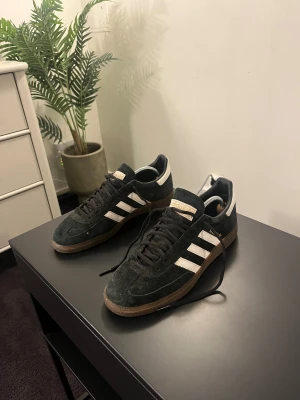 Adidas Spezial gröna sneakers mocka - Klassiska Adidas Spezial sneakers i grön mocka med vita ränder och gummisula. Skorna har snörning och den ikoniska Spezial-loggan i guld på sidan. Perfekta för alla olika stilar och alla olika användningsområden. 