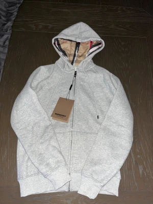 Grå hoodie från Burberry med dragkedja - Helt ny grå hoodie från Burberry, Säljer för att jag aldrig använt den! 