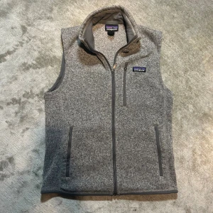 Grå patagonia fleece väst - Skick: Mycket bra, i prima skick förutom en bortklippt storleksetikett men är i storlek S.   Märke: Patagonia   Storlek: S, se gärna mått!   Färg: Grå fleece  Mått:                                                                    Armhåla till armhåla: 46cm                        Totallängd: 68cm