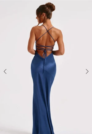 Balklänning - Säljer en marinblå balklänning från babyboo i satin med smala axelband och djup v-ringning. Klänningen har en hög slits framtill och öppen rygg med snörning som korsas och knyts baktill. Använd en gång och inga defekter. Skriv för fler frågor/bilder💙