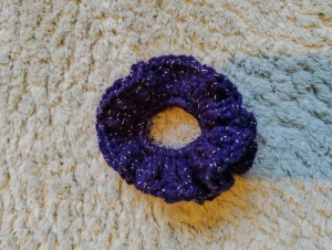 Lila glittrig hårsnodd scrunchie - Snygg lila handgjord scrunchie med glittriga inslag som ger extra shimmer till din frisyr. Perfekt för att sätta upp håret med stil och addera en färgklick. Den är mjuk och stretchig, vilket gör den bekväm att bära hela dagen. Virkad av mig om någon undrar! 🙃🤗