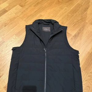 Oscar Jacobsson Väst - Svart väst, lite fläckig längs kragen men går att tvätta bort. Be gärna om fler bilder vid intresse. Västen är i storlek 46. Köptes här på plick men var inte riktigt rätt passform för mig. Nypris: 1199kr