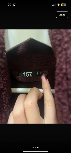 Mörk vinröd teddyjacka från 157 - Mysig teddyjacka i mörk vinröd färg från 157, storlek S. Jackan har en croppad passform, hög krage och dragkedja framtill. Perfekt för dig som gillar fluffiga och trendiga jackor med skön känsla. Materialet är fleece och jackan är långärmad. Knappast använd