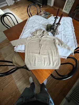 Beige hoodie med snörning - Snygg beige hoodie med huva och snörning framtill. Tröjan har långa ärmar och ribbade muddar vid ärmslut och nederkant. Mjuk och skön, perfekt för chill dagar. Passar dig som gillar enkel och clean stil. Aldrig använd säljer för den är för liten för mig 
