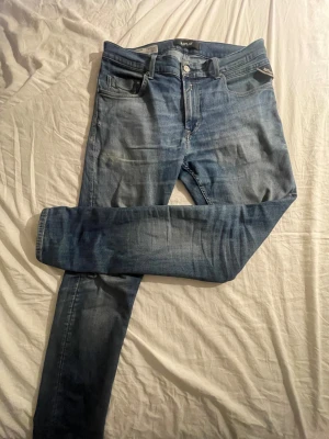 Replay blå jeans med straight fit - Snygga blå jeans från Replay med klassisk femficksdesign och läderpatch bak i midjan. Jeansen har en rak passform och är tillverkade i mjukt denimtyg. Perfekt för dig som gillar en tidlös och avslappnad stil.