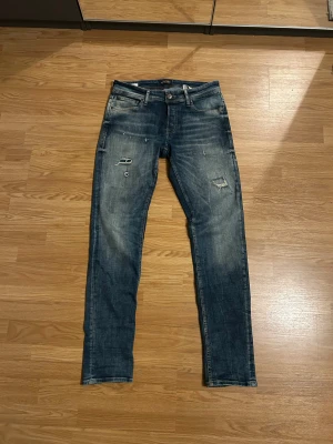 Jack & Jones jeans med slitningar - Riktigt snygga Jack  & Jones jeans med några små men snygga slitningar. Säljes pga av att jag har fler jeans som ser ungefär likadana ut och dessa kom inte riktigt till användning. Storlek 32/34. 