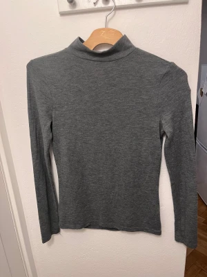 Grå polotröja med lång ärm - Elastiskt material. 