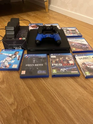 PlayStation 4 slim 800gb - PlayStation 4 i fint skick med två handkontroller (svart och blå), laddstation och 8 populära spel: FIFA 19, 21, 22, 23, PES 2017, Hidden Agenda, WRC 5, WRC 9. Allt fungerar som det ska, inga synliga eller typer av  defekter.