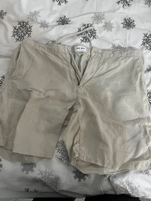 Beige linneshorts från East West - Snygga beige shorts från East West i mjukt och luftigt linne. De har en klassisk rak passform, dragkedja och knapp framtill samt diskret snörning i midjan. Perfekta för varma dagar och chill stil.