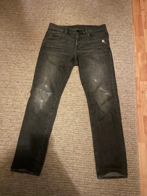 Mörkgrå g star jeans med slitningar använda fåtal ggr  - Gråa snygga g star jeans som sitter bra på benen de smil men dom är perfekta i passform snygga och slitningarna gör så dom sticker ut inköpta för 1500. 
