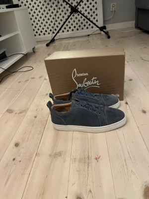 Blå mocka sneakers från Louboutin - Snygga blå sneakers från Christian Louboutin i mocka med klassisk röd sula och vita kanter. Skorna har rund tå, snörning och lyxig läderinsida. Perfekta för dig som vill sticka ut med exklusiv stil och detaljer. Storlek 39 passar 40 Nypris 13 000❌ vårt pris 2999✅