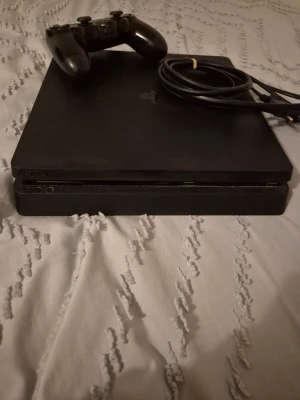 PlayStation 4 Slim - Sony PlayStation 4 Slim med en original handkontroll och strömkabel. Konsolen är i gott skick med några ytliga repor på ovansidan. Perfekt för gaming och multimedia. Allt du behöver för att komma igång direkt ingår.