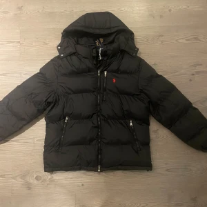 Ralph Lauren jacka  - Svart pufferjacka från Ralph Lauren med huva och flera dragkedjefickor. Jackan har det klassiska röda Polo-logot på bröstet och är vadderad för extra värme. Passformen är bra. Moddel är 187cm skriv vid frågor🙌🏼