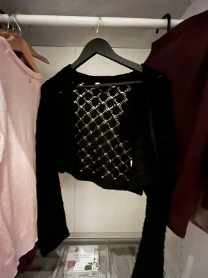 Svart bolerotopp från Ofelia M - Säljer en svart bolerotopp från Ofelia i storlek M. Toppen är croppad med långärmade armar och har ett snyggt hålmönster över hela plagget😁