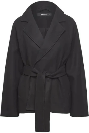 Svart omlottkappa från Gina Tricot - Stilren svart kappa från Gina Tricot med omlottknäppning och bälte i midjan. Jackan har bred krage och långa ärmar, perfekt för dig som gillar en clean och modern look. Enkel att matcha med allt i garderoben.