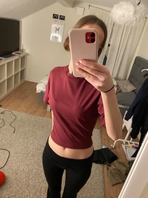 Vinröd croppad t-shirt från lager 157 - Säljer en vinröd croppad t-shirt från lager 157. T-shirten har korta ärmar, rund halsringning. Enkel och stilren modell som passar perfekt till jeans eller leggings.