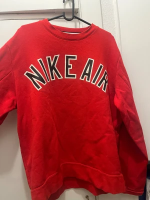 Röd Nike Air sweatshirt i bomull - Säljer en röd Nike Air sweatshirt i storlek M med stort tryck över bröstet. Tröjan har rund hals, långa ärmar och är tillverkad i 80% bomull och 20% polyester. Perfekt för dig som gillar sportig och avslappnad stil.