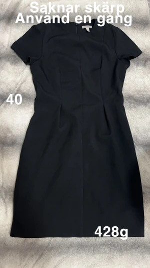 Svart kortärmad klänning - Stilren svart klänning med korta ärmar och rund hals. Modellen är figurnära och har en enkel, klassisk design utan mönster eller detaljer. Perfekt för dig som gillar minimalistisk stil och vill ha en klänning som funkar till många tillfällen.🌸 Använd en gång. Saknar skärp. Storlek 40