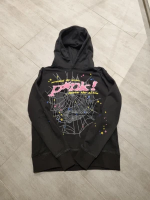Svart hoodie från pink - Svart hoodie från Pink! med stor spindelnätsprint och färgglada stjärnor på framsidan. Texten 'nevermind the spiders, before the slime' i gult och rosa. Baksidan har en gul stjärna med logga. Mjuk bomullskänsla och huva för extra chill vibe.