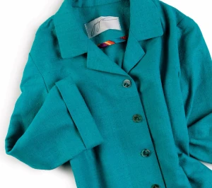 Turkos kavaj i linne från Judy J - Snygg turkos kavaj från Judy J med klassisk krage och knäppning framtill. Jackan är tillverkad i linne och har en stilren look med raka linjer och knappar i matchande färg. Perfekt för dig som vill sticka ut med färg och stil.