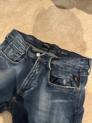 Replay Anbass blå jeans herr w-33 l-32.         1 - Snygga Replay Anbass jeans i blå tvätt med slitningar och klassiska fem fickor. Modellen har en smal passform och är tillverkad i stretchigt jeanstyg för extra komfort. Perfekt för dig som gillar en modern och stilren look.