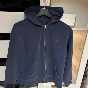 Mörkblå hoodie från Ralph Lauren - En mörkblå Ralph Lauren Hoodie som är väldigt skön och i  bra skick. Storlek är XL i barnstorlek, men den sitter som en vanlig S. Bara att skriva om de finns några frågor eller funderingar👍🏼