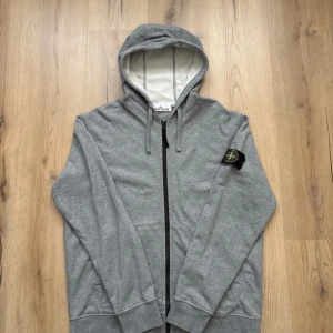 Stone Island grå zip hoodie - Äkta grå stone island zip hoodie i storlek XL men passar som L. Knappt använd nästan nytt skick! Qr kod som leder direkt till officiella hemsidan och alla lappar kvar
