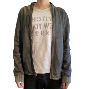 Tigha läderjacka - Tigha läderjacka i storlek M. Är gjort av äkta läder. Har några små fläckar på ryggen (syns på sista bilden). Jag på bilden är 180 cm. Mått: axelbredd - 47 cm, längd - 63 cm. Skriv för fler bilder och frågor!