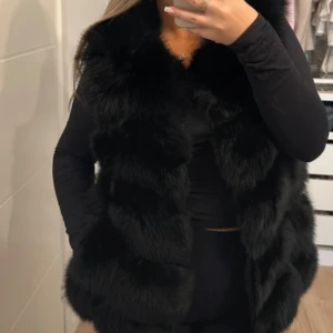 Svart fluffig pälsväst - Säljer en svart pälsväst med riktigt fluffig och mjuk känsla. Västen är ärmlös och har en klassisk rak passform som ger en lyxig vibe. Perfekt att slänga över en långärmad tröja för en cool look för mer bilder och frågor skriv gärna ❤️❤️
