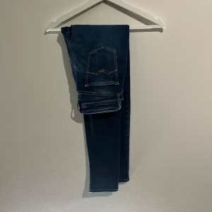 Replay jeans i mörkblå - Säljer ett par snygga Replay jeans i mörkblå tvätt med klassiska kontrastsömmar och femficksdesign. Modellen har smal passform och raka ben, perfekt för dig som gillar en stilren look. Materialet är stretchigt jeans för extra komfort.