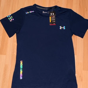 Under Armour t-shirt  - Snygg marinblå t-shirt från Under Armour med reflekterande logga. Tillverkad i andningsbart material. Klassisk passform med korta ärmar och rund hals. Hör av dig vid fler frågor eller funderingar!