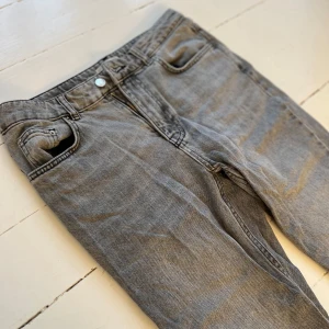 Grå lågmidjade bootcut jeans  - Snygga grå jeans med raka ben och klassisk femficksdesign. Jeansen har normal midja och är tillverkade i mjukt denimtyg. Perfekta för dig som gillar en enkel och tidlös stil.