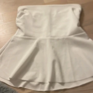 Vit topp från Missay - Supersöt vit topp  från Missay med utsvängd form och hög midja. Toppen  är enkel och stilren, perfekt för dig som gillar en clean look. Materialet känns mjukt och följsamt mot huden.