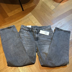 Grå loose fit jeans från Kappahl( HELT NYA) - Snygga grå loose fit jeans från Kappahl i midwaist-modell. Jeansen har klassisk femficksdesign, raka ben och är tillverkade i ett mjukt bomullstyg utan stretch. Perfekta för en avslappnad och trendig look. Och för dig som gillar lite större jeans
