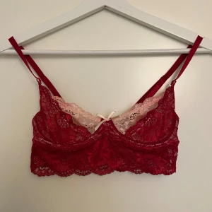 Röd spetsig linnetopp från SHEIN - Säljer en röd spetsig linnetopp från SHEIN i storlek XXS. Toppen har tunna axelband, ljusrosa spetsdetalj upptill och en liten rosett framtill. Materialet är syntet med stretch och den har en romantisk vibe med blommönstrad spets.