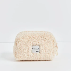 Beige fluffig necessär från Gina Tricot - Supermjuk och fluffig necessär i beige teddy-material från Gina Tricot. Rektangulär form med dragkedja upptill och liten etikett framtill med texten 'You are pretty'. Perfekt för smink eller småprylar.