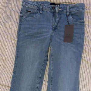 Ljusblå jeans från S.C.W. 30/32 - Ljusblå jeans från S.C.W. med klassisk femficksdesign, snygga kontrastsömmar och läderpatch bak i midjan. Jeansen har dragkedjegylf och raka ben. Perfekta för dig som gillar en enkel och stilren look. Har aldrig använt prislapp finns kvar 