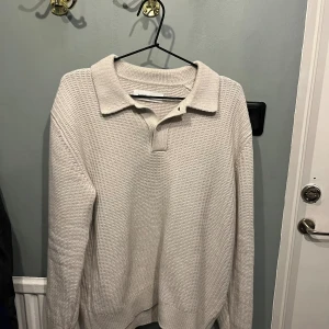 Beige stickad pikétröja från Samsøe Samsøe - Snygg beige stickad pikétröja från Samsøe Samsøe med klassisk krage och knäppning framtill. Tröjan har lång ärm och ett strukturerat mönster i materialet som ger en cool och avslappnad vibe. Perfekt för lager-på-lager under hösten och vintern storlek S men sitter bra på M.