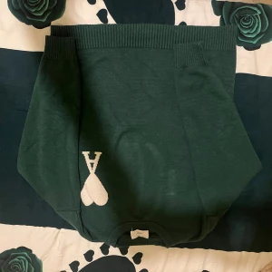 Mörkgrön kjol med hjärtdetalj - Supersnygg mörkgrön kortkjol från AMI Paris med bred ribbad midja och vit hjärtdetalj framtill. Kjolen har en enkel, clean look och är perfekt för dig som gillar stilrena plagg med en twist.