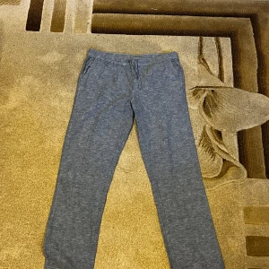 Grå mjukisbyxor från Livergy - Snygga grå linnebyxor från Livergy med dragsko i midjan och raka ben. Byxorna har sidfickor och är tillverkade i ett mjukt bomullsmaterial som är perfekt för chill dagar. Passar dig som gillar en avslappnad och enkel stil.