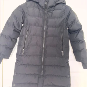 Svart barn jacka - Säljer en jacka för barn perfekt till vinter tider med reflexer och ett tjockt material med luva. 