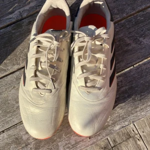 Adidas Copa vita fotbollsskor strl 38 - Säljer ett par Adidas Copa fotbollsskor i vitt med svarta och röda detaljer. Skorna har klassisk snörning